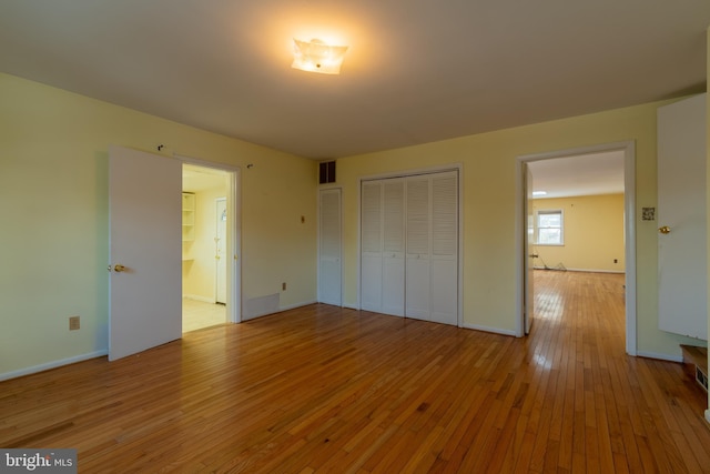 unfurnished bedroom with ensuite bathroom, light hardwood / wood-style floors, and a closet