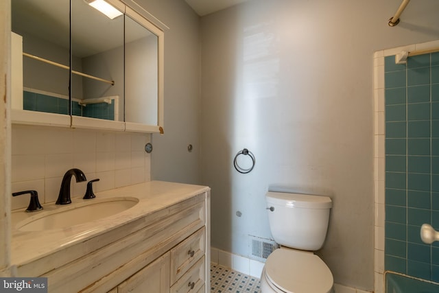 bathroom featuring vanity, toilet, a shower, and backsplash