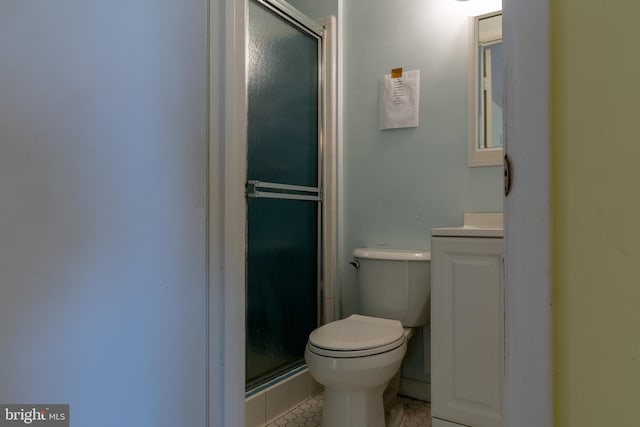 bathroom featuring vanity, a shower with shower door, and toilet