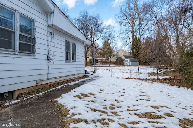 snowy yard with a storage shed