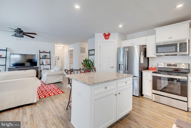 kitchen featuring light stone countertops, stainless steel appliances, light hardwood / wood-style flooring, white cabinets, and a kitchen island