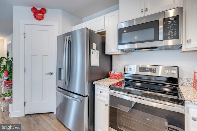 kitchen featuring light stone countertops, stainless steel appliances, and white cabinetry