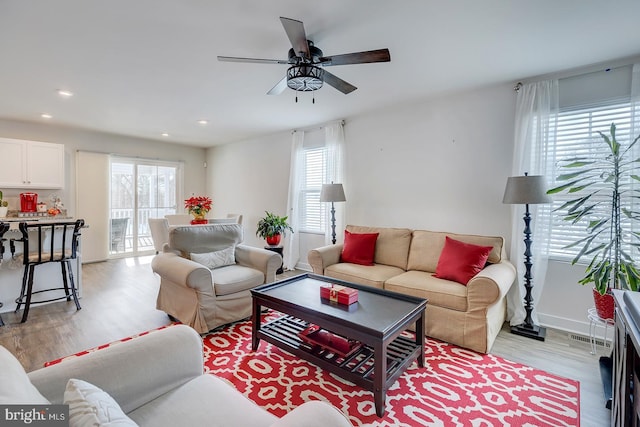 living room with ceiling fan, plenty of natural light, and light wood-type flooring