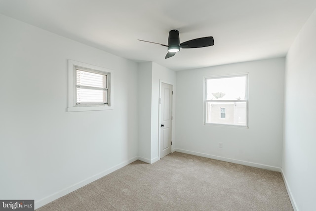 empty room with ceiling fan, plenty of natural light, and light colored carpet