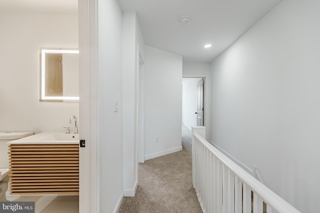 hallway featuring light colored carpet and sink