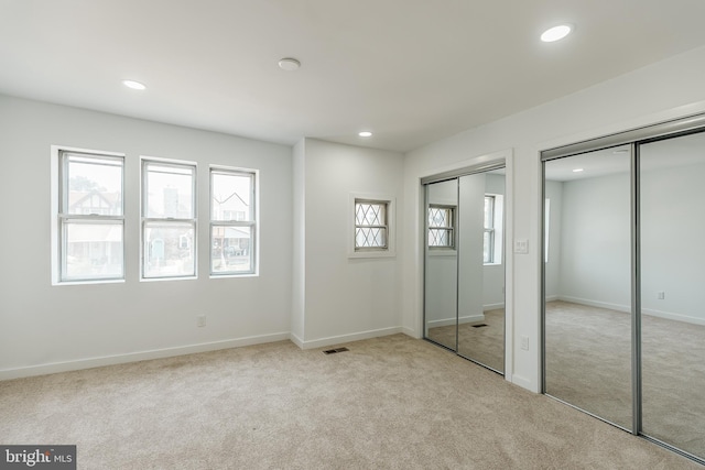 unfurnished bedroom with multiple closets and light carpet