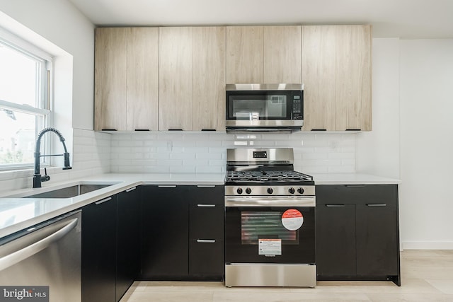 kitchen with backsplash, light brown cabinets, sink, and stainless steel appliances