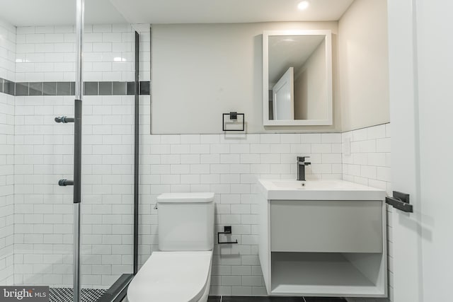 bathroom featuring an enclosed shower, vanity, toilet, and tile walls