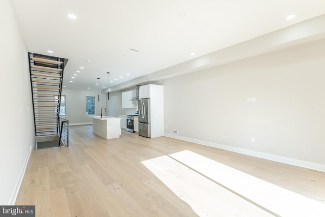 unfurnished living room with light hardwood / wood-style floors and sink