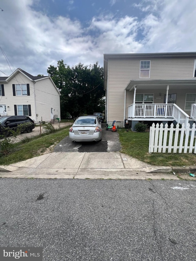 view of front of home with a porch, driveway, and a fenced front yard