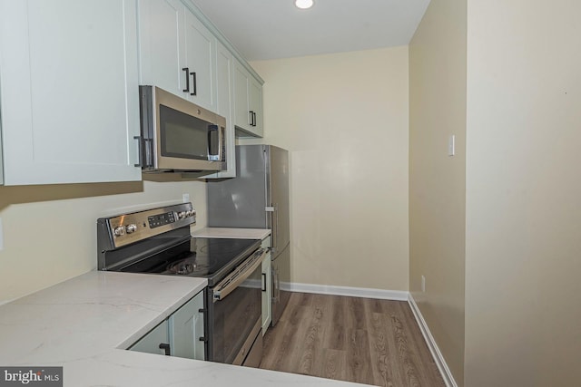 kitchen featuring white cabinetry, light stone counters, light wood-type flooring, and appliances with stainless steel finishes