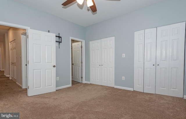 unfurnished bedroom with carpet, ceiling fan, and multiple closets