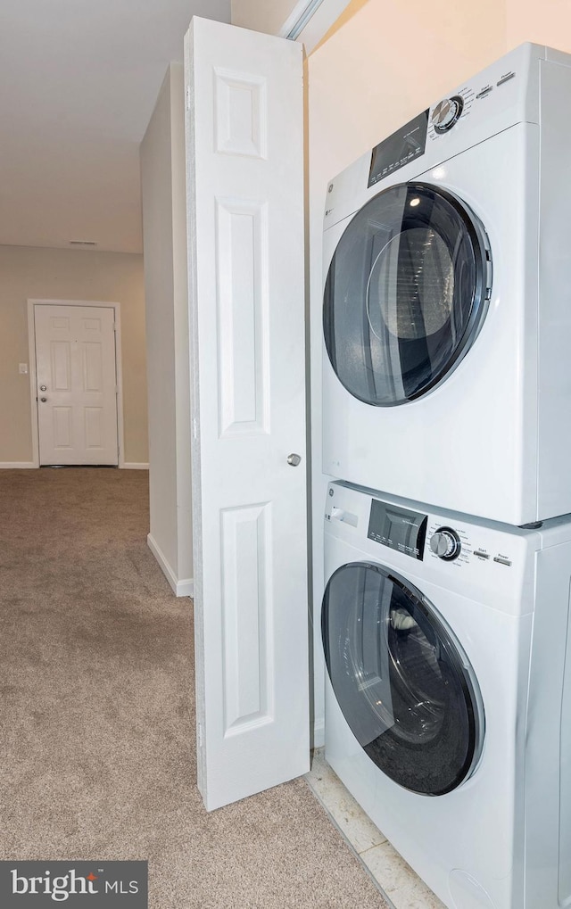 laundry room featuring light carpet and stacked washer / drying machine