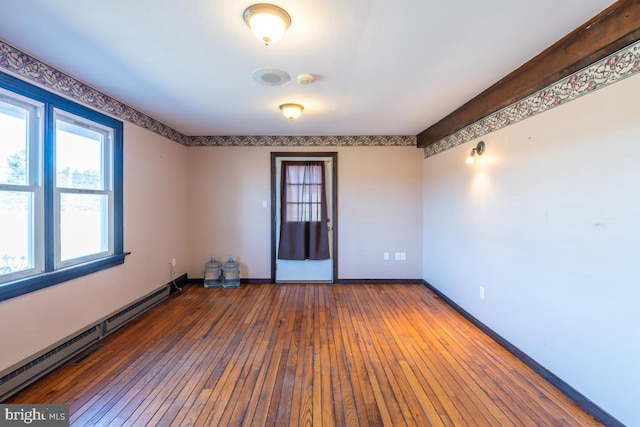 empty room featuring a baseboard heating unit and hardwood / wood-style floors