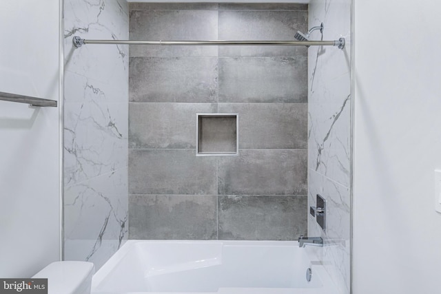 bathroom featuring toilet and tiled shower / bath