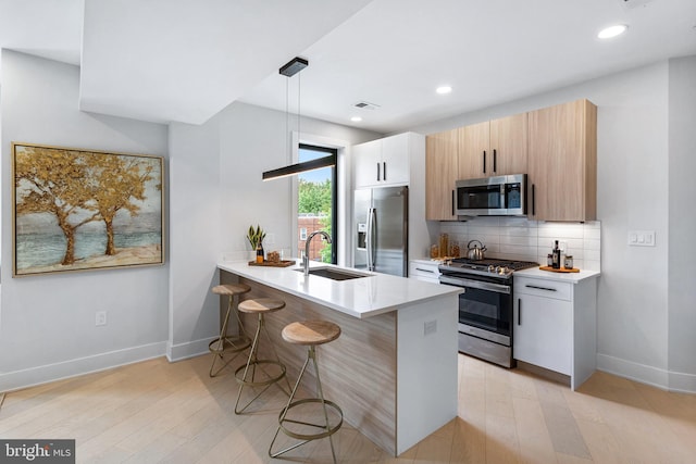 kitchen featuring sink, hanging light fixtures, stainless steel appliances, a kitchen breakfast bar, and kitchen peninsula