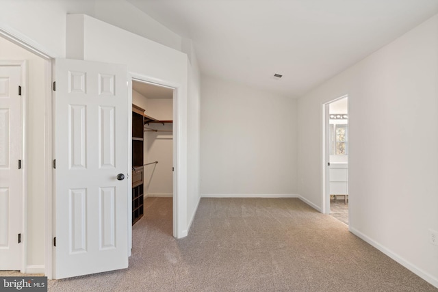 unfurnished bedroom featuring a closet, a spacious closet, and light carpet