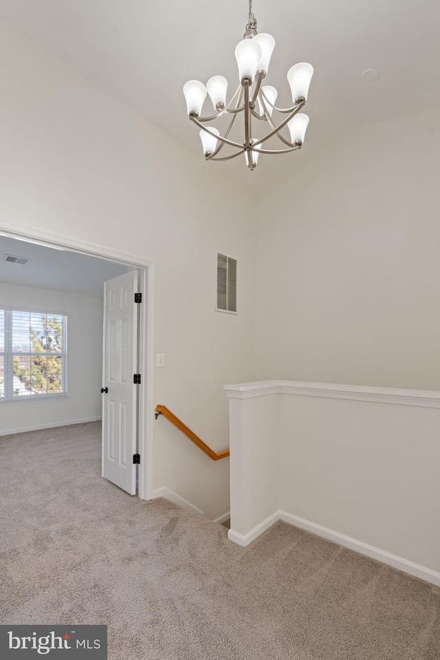 carpeted spare room featuring a notable chandelier