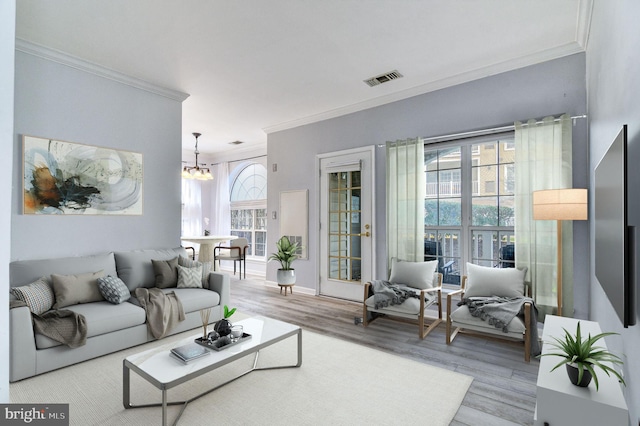 living room featuring crown molding, light hardwood / wood-style floors, and a chandelier