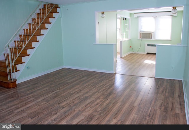 unfurnished living room with dark wood-type flooring, cooling unit, and radiator heating unit