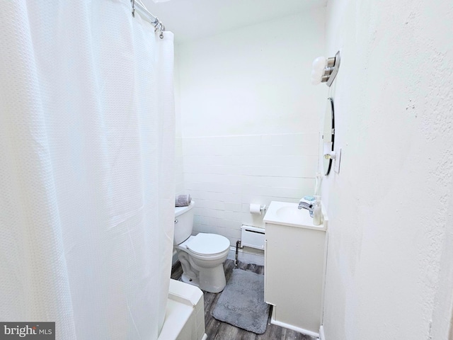 bathroom with a shower with shower curtain, vanity, a baseboard radiator, hardwood / wood-style flooring, and toilet