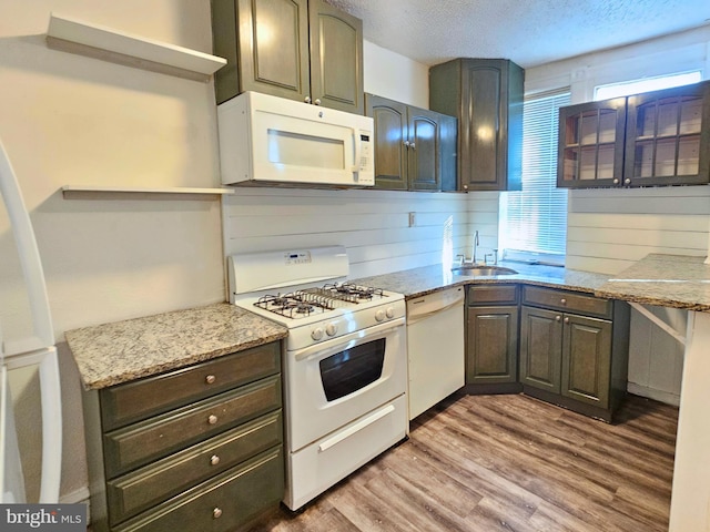 kitchen featuring light stone counters, sink, wood-type flooring, and white appliances