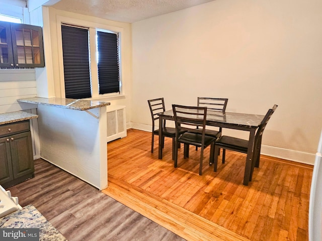 dining room featuring wood-type flooring, a textured ceiling, and radiator