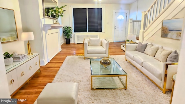 living room featuring radiator, light hardwood / wood-style floors, and a baseboard heating unit