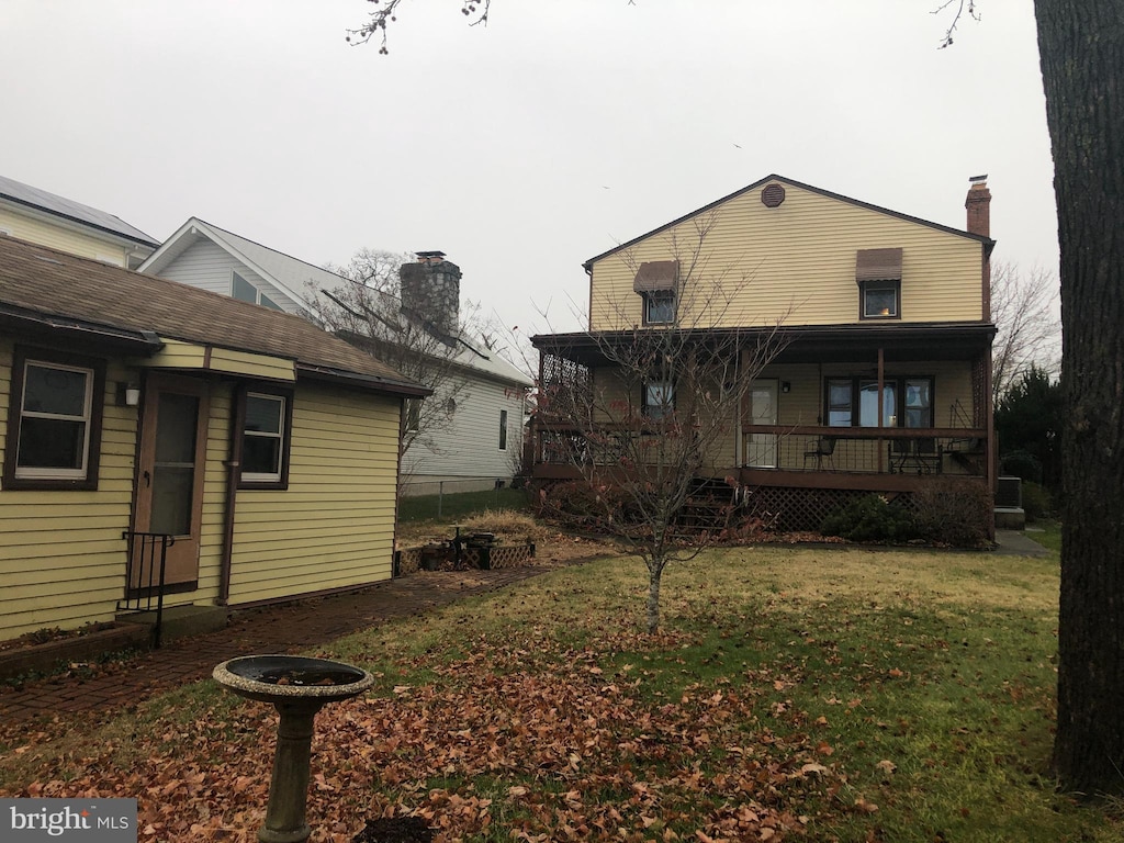 rear view of house featuring a lawn and a porch