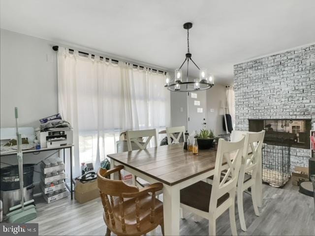 dining room with an inviting chandelier, hardwood / wood-style floors, and a fireplace