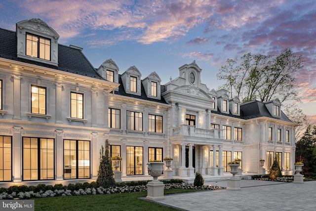 back house at dusk featuring a balcony