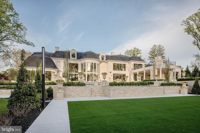 rear view of property with a lawn and a balcony