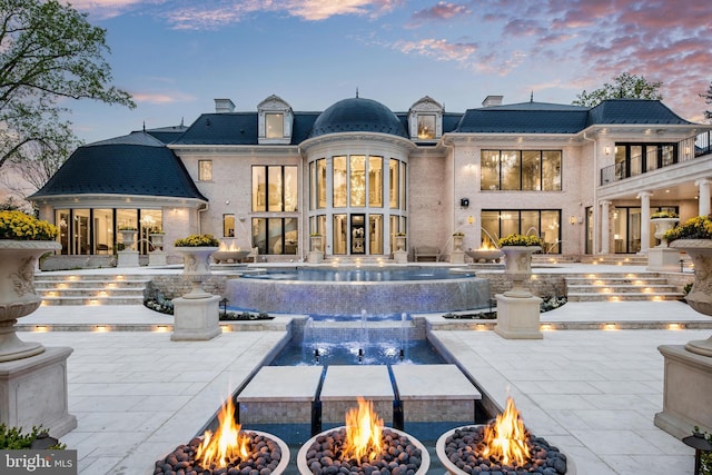 back house at dusk with an outdoor fire pit