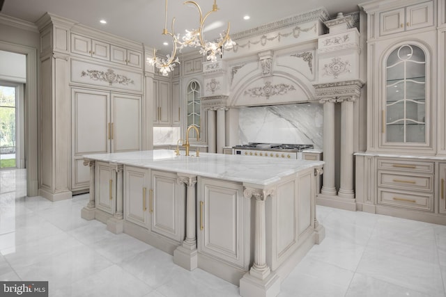 kitchen featuring custom exhaust hood, a center island with sink, hanging light fixtures, cream cabinetry, and stainless steel gas cooktop