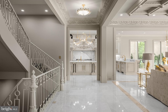 hall with sink, crown molding, and an inviting chandelier