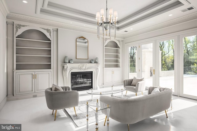 living room with built in shelves, a raised ceiling, crown molding, and a chandelier