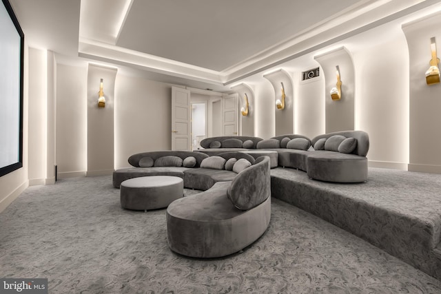 home theater room featuring carpet and a raised ceiling