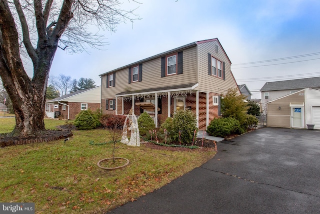 view of front facade with covered porch, a garage, a front lawn, and an outdoor structure