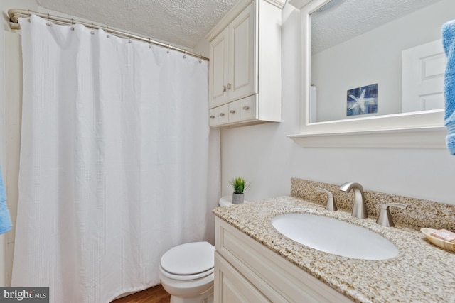 bathroom featuring a textured ceiling, toilet, and vanity