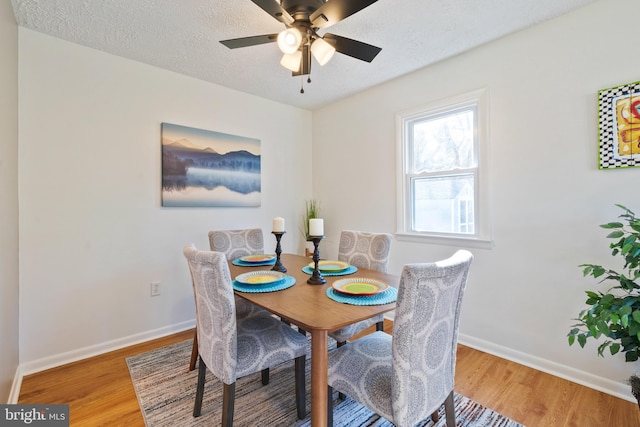 dining space with a textured ceiling, ceiling fan, and wood-type flooring