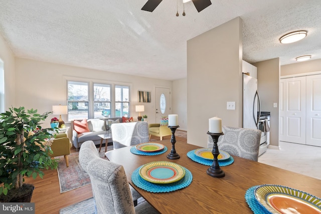 dining room featuring a textured ceiling, ceiling fan, and light wood-type flooring