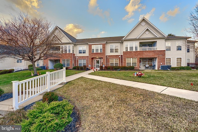 townhome / multi-family property featuring central air condition unit and a front yard