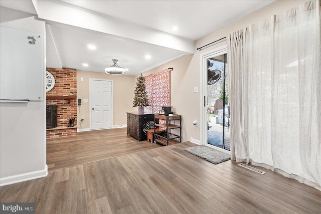 foyer featuring wood-type flooring and a brick fireplace