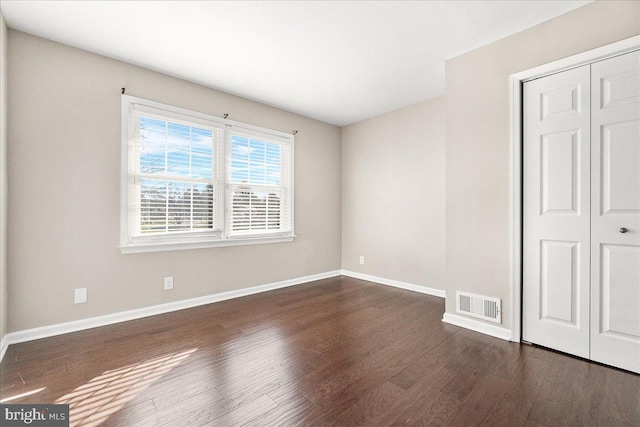 unfurnished bedroom featuring a closet and dark hardwood / wood-style flooring