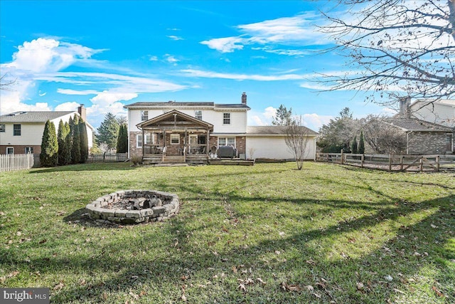 rear view of property featuring a lawn and an outdoor fire pit