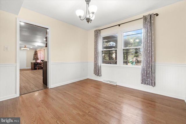 unfurnished dining area with hardwood / wood-style floors and a notable chandelier