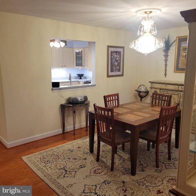 dining space featuring light hardwood / wood-style flooring, a chandelier, and sink