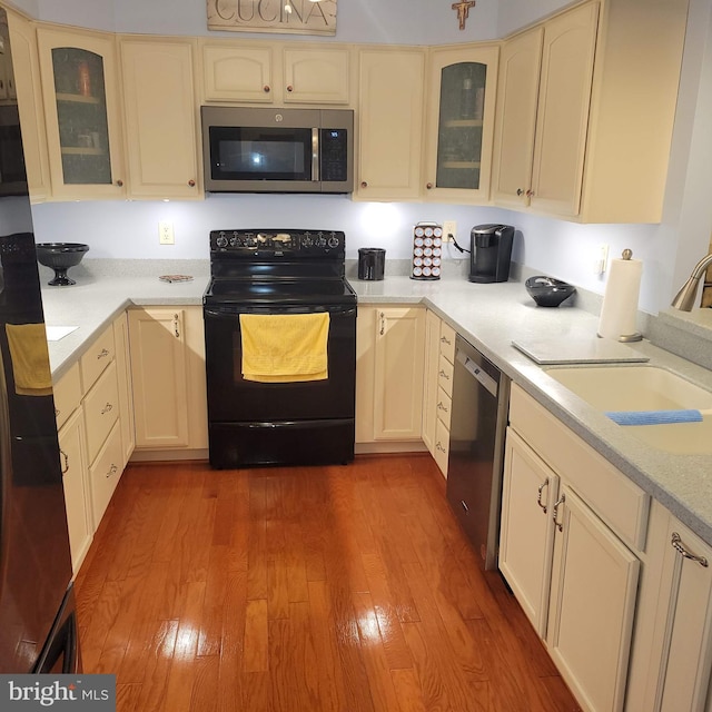 kitchen with cream cabinetry, light hardwood / wood-style floors, sink, and appliances with stainless steel finishes