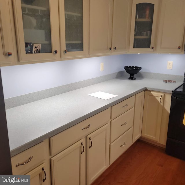 kitchen with electric range, dark wood-type flooring, and cream cabinetry