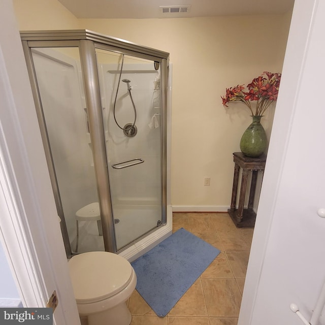 bathroom featuring toilet, tile patterned floors, and an enclosed shower